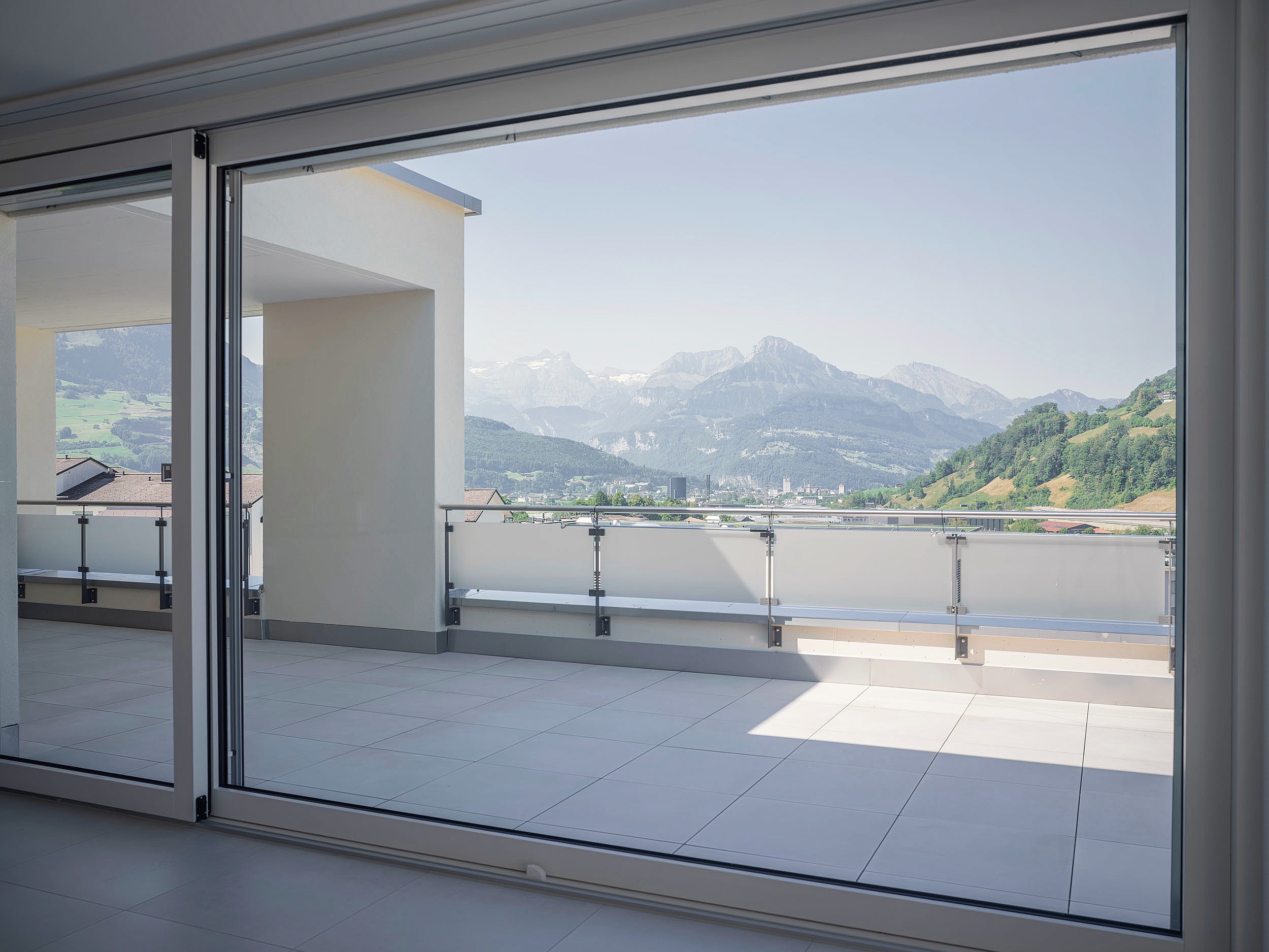 Offene Schiebetür vom Wohnraum auf die Terrasse mit Bergpanorama